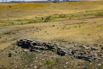 An unusual view in the Rostov region of the stony Zaitsev rocks, around green deciduous trees, dry yellow grass, blue sky and Sunny warm summer light