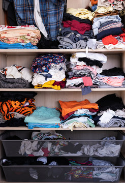 Shelves On An Open Closet Full Of Colorful Clothes Clustered Together