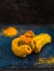 Dried turmeric roots on a navy blue ceramic dish.