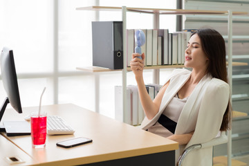 Asian woman woking at her desk office with fan and water in summer time
