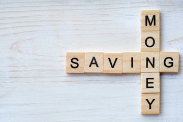 The words "SAVING, MONEY" made with wooden letters isolated on old wood background.