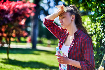 Young tired woman suffering from hot weather outdoors in a summer day - obrazy, fototapety, plakaty