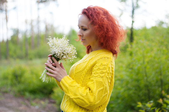 close up red haired pretty girl posing with bouquet of white flowers in yellow sweater. gentle image young woman