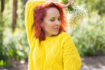 red haired beautiful girl with closed eyes holding bouquet of white flowers in yellow sweater