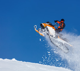 Extreme sport race snowmobiles. Snowmobile in high jump above track. Sportsman on snowmobile. Winter competition, sunny day. Trick against blue sky. Snow motor sports Copy space.