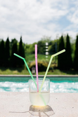 Glass of lemonade with three straws by the swimming pool