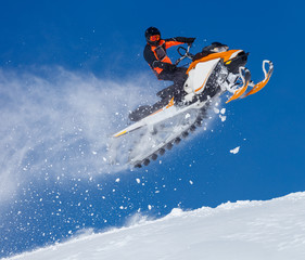 snowmobile rider jumping through snow. RIDER MAN WITH HELMET JUMPING WITH SNOWMOBILE BETWEEN SKY ON WINTER. a bright suit and a snow motorcycle. Extreme winter sport. high resolution and photo quality