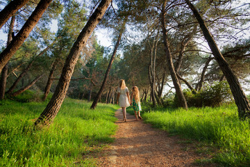 Mother and daughter walking on a path in a pine forest, Croatia
