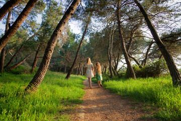 Fototapeta premium Mother and daughter walking on a path in a pine forest, Croatia