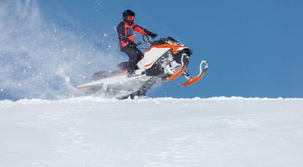 Fototapeta na wymiar The sportsman on a snowmobile. Recreation concept on nature in winter holidays. a bright suit and a snow motorcycle. Winter sports. high resolution and photo quality