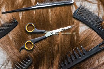 A female long hair, scissors and hair brushes on the barber table background.