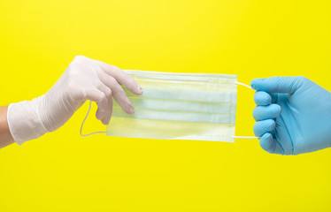 yellow background and hands in medical gloves.male and female hands in medical gloves pull on a...