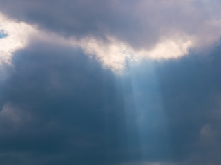 The sun's rays create a cone of light emanating from dense dark clouds