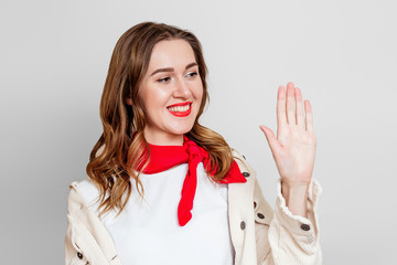 Left-handed girl holds her left hand in front of her, smiles and looks at her isolated over light gray wall background, celebrating left-handed day