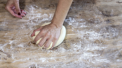 Cook hands making pizza dough and preparing with tomato, mushrooms, ham, mozzarella and parmesan cheese.