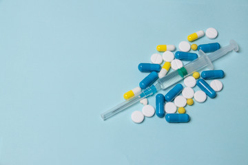 Medical syringe and pills on a dark blue background, health and vaccination concept.