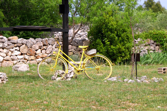 Old bike, painted yellow and set as decoration in the Mediterranean village in Dalmatia region, Croatia.