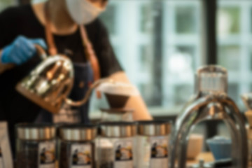Abstract blur restaurant and coffee shop cafe interior for background. Young woman using kettle for make tea or black coffee.