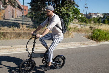 Caucasian attractive man rides his e - bike on the street to go to work and in his leisure. Electric bibycle concept. Ecologic mobility concept. Modern transportation. Electric biking . Cycling man 
