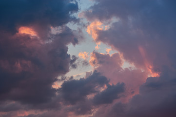 Sullen, dark-blue clouds through which the sun's rays break