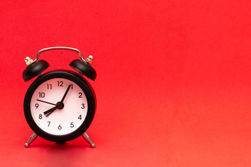 Black alarm clock on a red background, Place for text, copy space. The photo