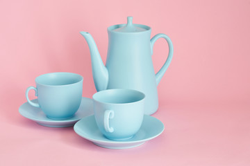 minimalism concept with light pastel colored blue cups teapot and plate on pink background.