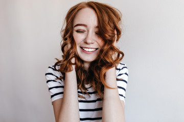 Blissful european woman in casual outfit laughing with eyes closed. Indoor photo of debonair ginger girl expressing excitement.