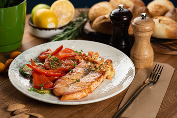 grilled salmon steak with red pepper and zucchini with cream sauce on a wooden table. close-up