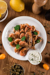 fried shrimp with white sauce and microgreens on a wooden table. top view. close-up