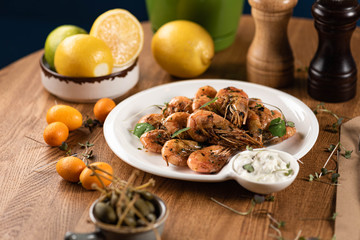 fried shrimp with white sauce and microgreens on a wooden table. 