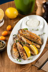 fried red mullet with white sauce and micro-greens on a wooden table. top view