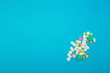 Heap of colorful pills on blue background