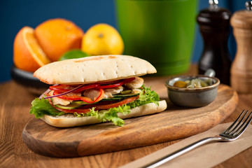 panini or hot sandwiches with beef, ham, herbs and cheese, tomatoes and red pepper on a wooden cutting board