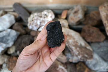 hand holding a piece of raw lignite.
