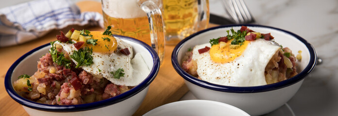 Norddeutscher Hamburger Labskaus mit Rindfleisch Corned Beef, Rote Beete, Kartoffeln, Saure Gurken, Spiegelei, Rollmops und Bier auf Marmor