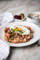 Norddeutscher Hamburger Labskaus mit Rindfleisch Corned Beef, Rote Beete, Kartoffeln, Saure Gurken, Spiegelei und Rollmops auf Teller