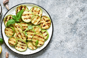 Grilled zucchini with sauce on concrete background. View from above.