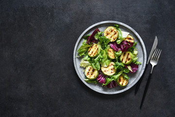 Mix salad with grilled zucchini and sauce on a black background.Top view with copy space.