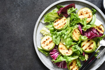 Mix salad with grilled zucchini and sauce on a black background.Top view with copy space.