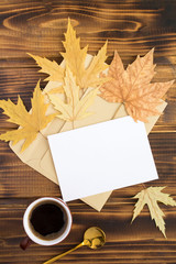 White paper for text, black coffee in the ceramic cup and dry  leaves on the brown wooden background. Top view. Copy space. Location vertical.