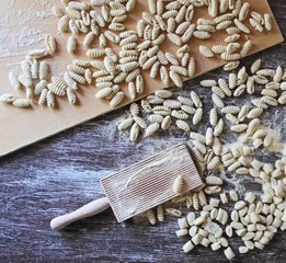 Italian typical pasta and kitchen utensils on wood table. Malloreddus of semolina in the making....