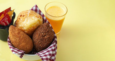 delicious brazilian snacks and fresh juice on a yellow table viewing from above