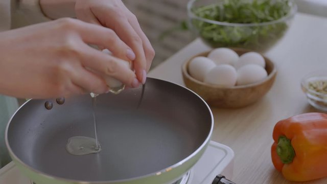 Close up of unrecognizable woman standing in the kitchen and making fried eggs