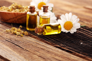 Chamomile Composition with essential oil and chamomile flowers on wooden rustic table