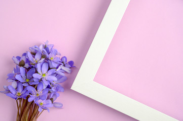 Bouquet of blue flowers and white frame on a purple background Top view, copy space.