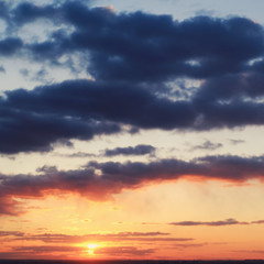 Dark clouds and orange sun in the evening haze