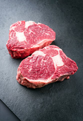 Rohes dry aged Wagyu Rib-Eye Steak vom Rind als closeup auf einem schwarzen Board mit Textfreiraum  