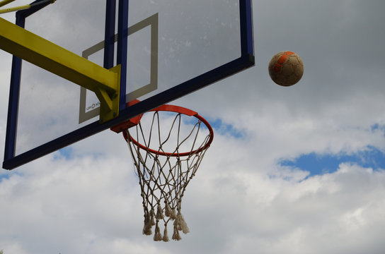 football flies to the basketball ring against the cloudy gray sky