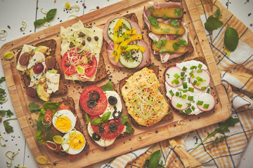 Tasty, homemade small sandwiches with various ingredients served on wooden chopping board
