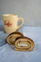Two slices of sponge roll on textile surface and a cup of coffee